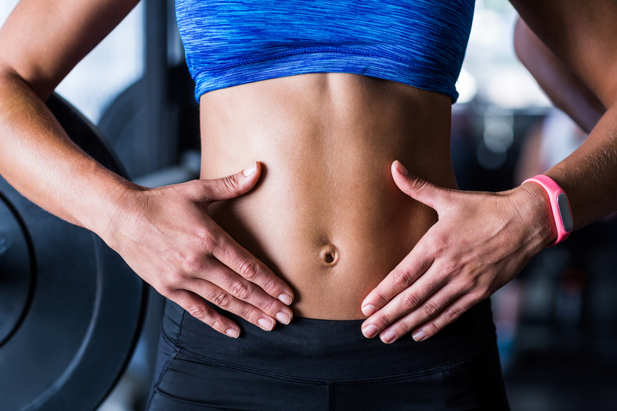 Midsection of athlete touching belly in gym