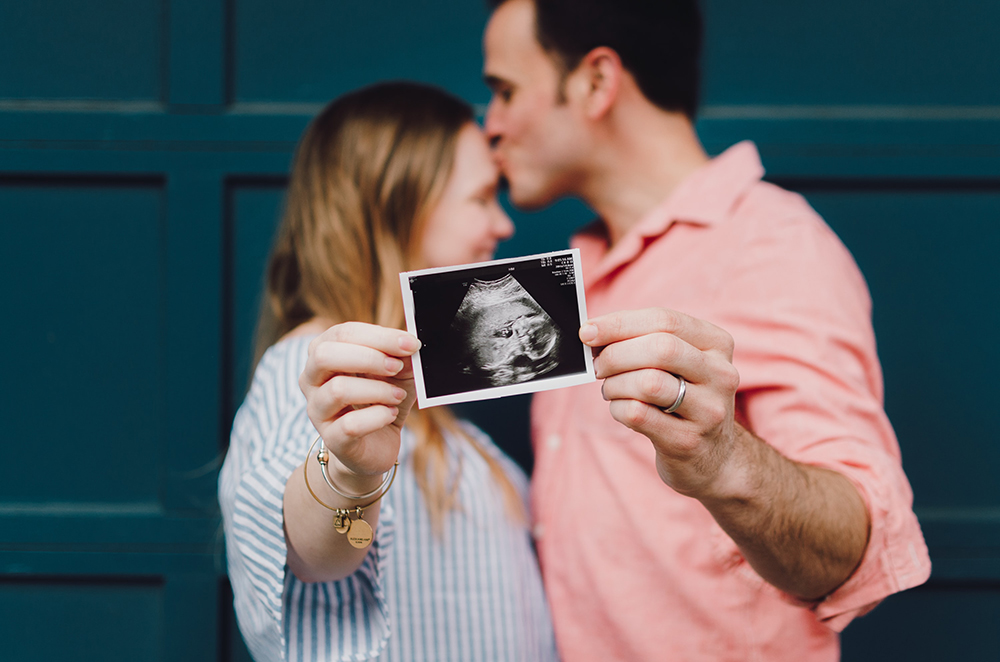 A happy couple holding an ultrasound image, after combining hCG and testosterone therapy