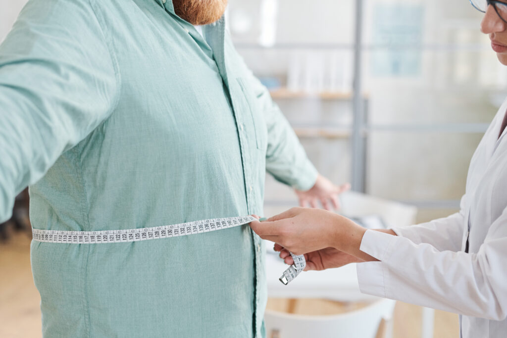 Doctor measuring obese man's stomach in an assessment of semaglutide for weight loss
